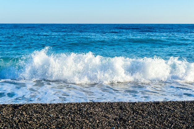 Zeegolven breken op een steenachtig strand en vormen sprays en spatten