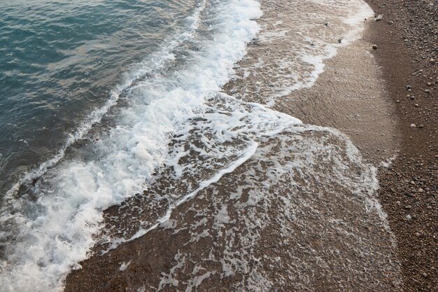 Zeegolven en zijaanzicht van het zandstrand van steen