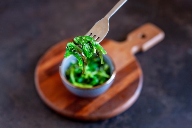 Zeekelp in de kom met vork op houten keukenbord