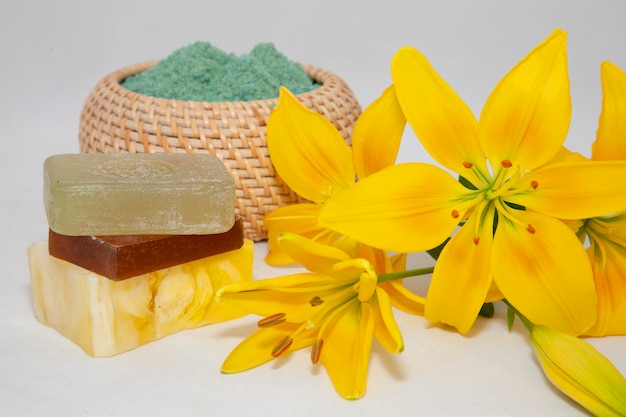 Foto zeep met natuurlijke ingrediënten en gele leliebloemen op witte achtergrond