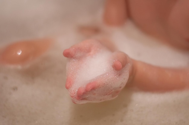 Zeepschuim in de handen van een kind op de achtergrond van een badkamer met schuim