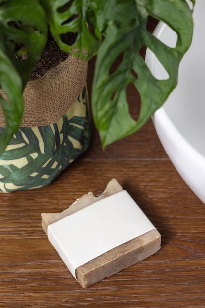 Foto zeepstaaf met leeg etiket op bad houten toonbank bij monstera plant close-up mockup