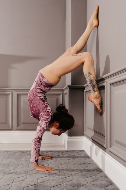 Zeer flexibel jong meisje dat yoga in de minimalismekamer doet