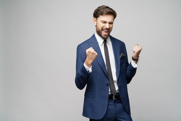 Zeer gelukkige succesvolle winnaar gesturing zakenman over grijze achtergrond