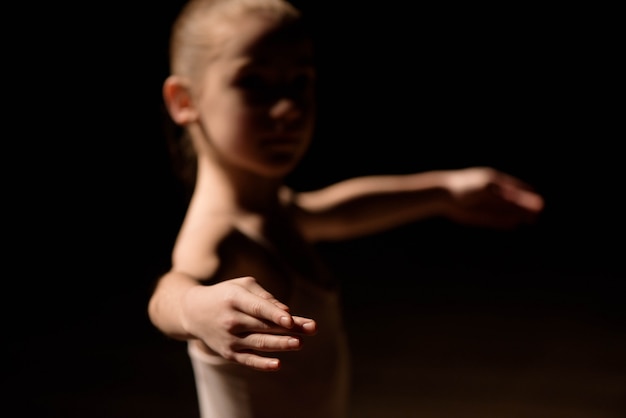 Zeer jonge ballerina poseren op een zwarte achtergrond