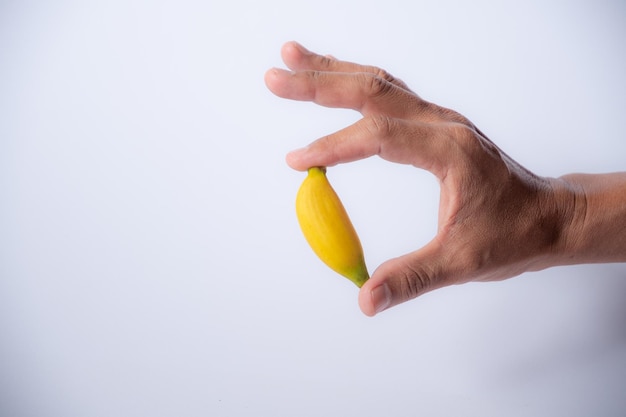 Zeer kleine banaan in de hand witte witte achtergrond