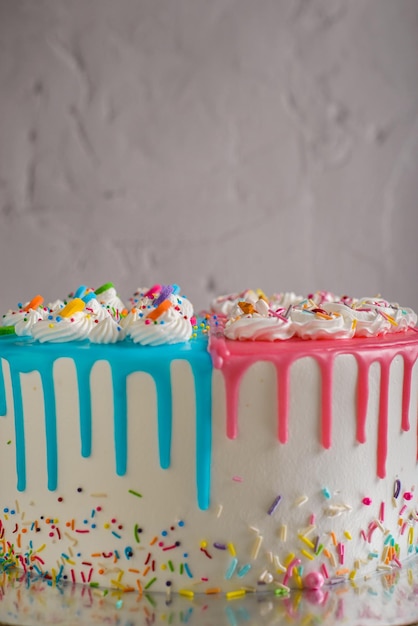 Zeer kleurrijke cake versierd met blauw en roze glazuur op een cementtafel