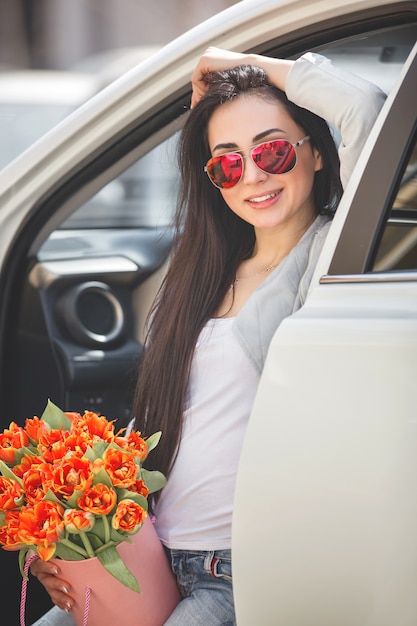 Zeer mooie vrouw in de auto met bloemen