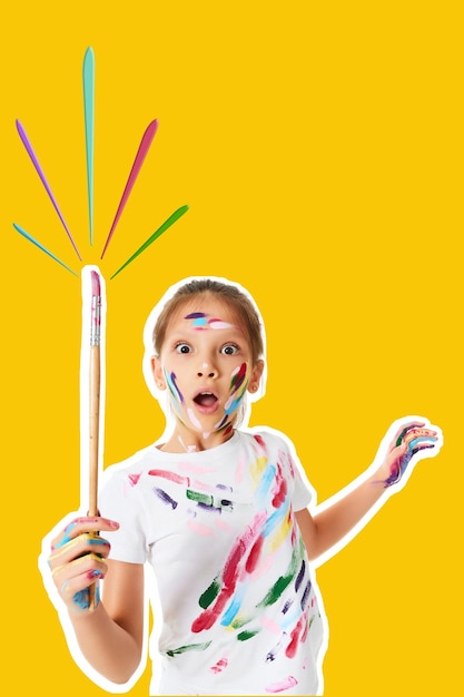 Zeer opgewonden klein kindmeisje in kleurrijke verf met penseel in één hand