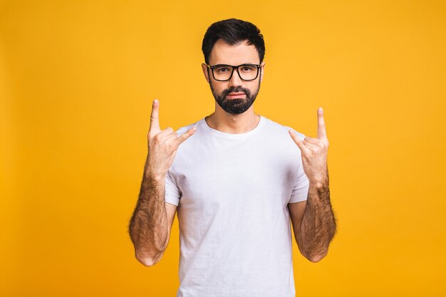 Zeer opgewonden tevreden man met baard toont rock-'n-roll-gebaar met vingers, plezier rusten op concert.