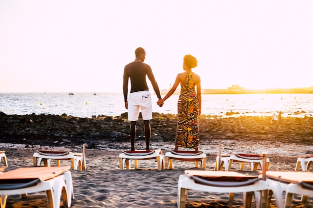 Zeer romantische zwarte jonge jongens model paar Afrikaanse race handen staan op zoek naar zichzelf met een zonsondergang in het oppervlak. zandstrand en stoelen gesloten voor een oneindig liefdesconcept