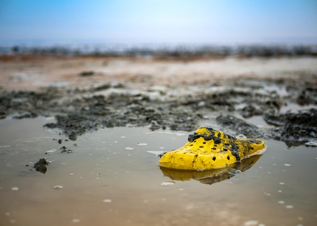 Zeer vuile gele schoen aan de oever van een zoutmeer op een zonnige dag