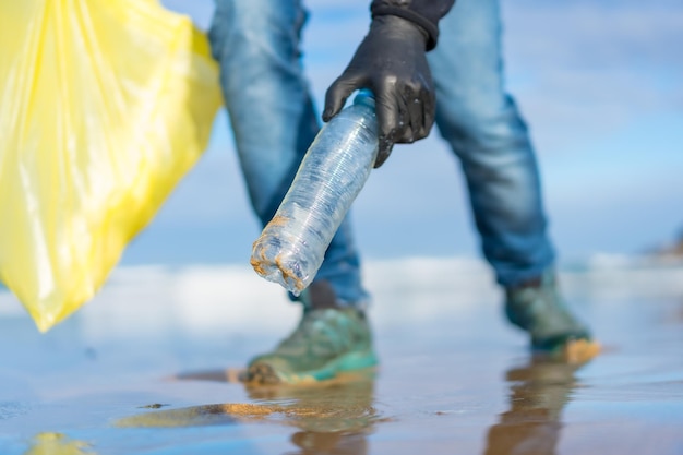 Zeeverontreiniging onherkenbare persoon die afval en plastic verzamelt op het strandecologieconcept