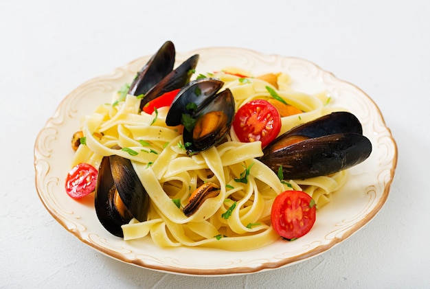 Zeevruchten fettuccine pasta met mosselen op witte achtergrond