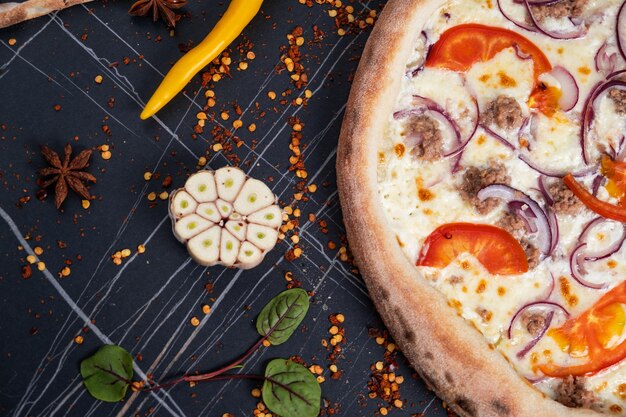 Foto zeevruchten italiaanse pizza met tonijnfilet uien verse kruiden en mozzarella op tomaten geserveerd ongesneden op een kruidige basis gezien van boven