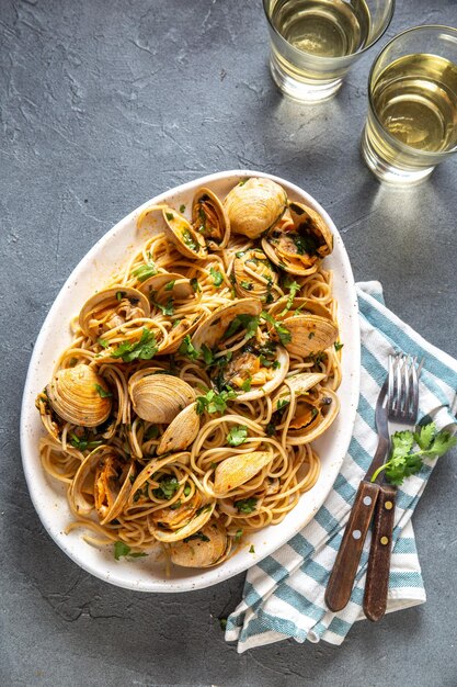 Foto zeevruchten pasta italiaanse spaghetti alle vongole mosselen spaghetti op een wit bord met witte wijn grijs