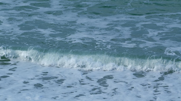 Foto zeewater golven golf na golf geveegd naar de kust langzame beweging