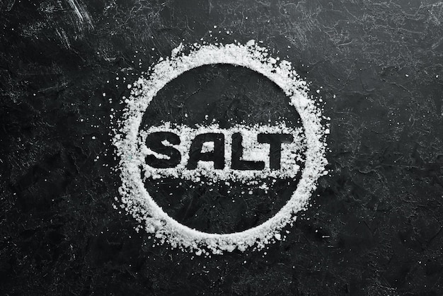 Zeezout met het opschrift SALT Op een zwarte stenen achtergrond Spabehandelingen Bovenaanzicht Vrije ruimte voor uw tekst
