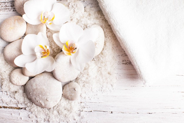 Foto zeezout, rebbles met orchideeën en witte handdoeken, spa-concept