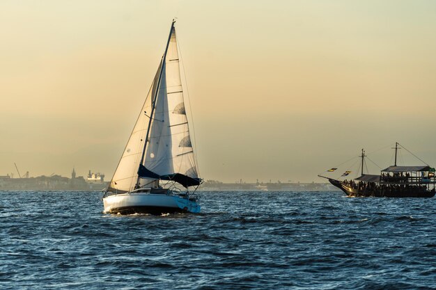 Zeilboot in Guanabara Bay in Rio de Janeiro Brazilië met een heuvel op de achtergrond Mooi landschap met de zee bij zonsondergang Zeilboten en speedboten in de baai