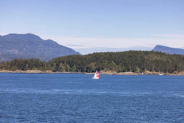 Zeilboot in het Canadese landschap bij de oceaan en de bergen