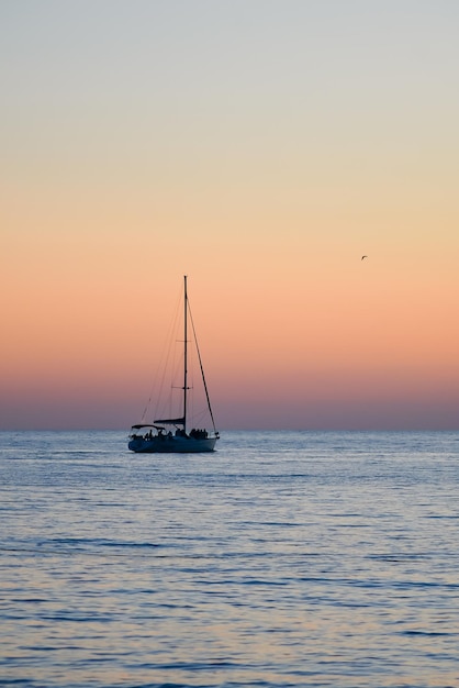 Zeilboot tegen de achtergrond van de avondrood in de zee.