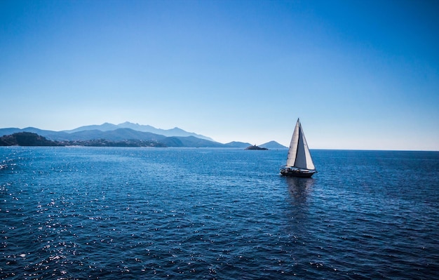 Zeilboot zeilt op zee tegen een heldere blauwe lucht