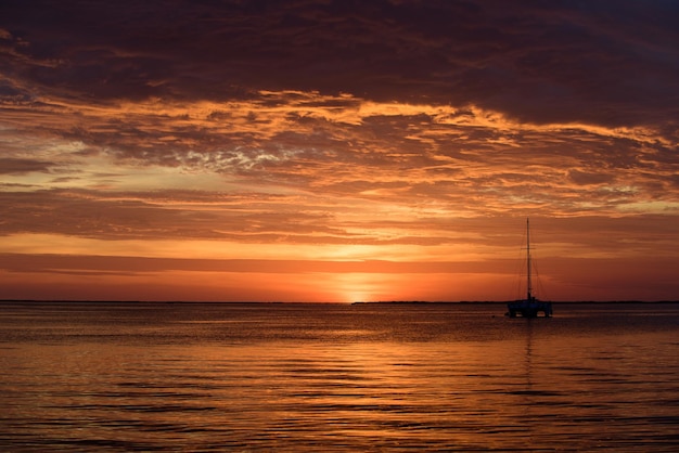 Zeilboten op de oceaan bij zonsondergang boot met zeilen zeejacht zeilen langs water