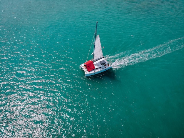 Zeilschip jachten met witte zeilen en rode luifel van de zon voor passagiers op open zee. Luchtfoto - drone-weergave naar zeilboot in winderige staat