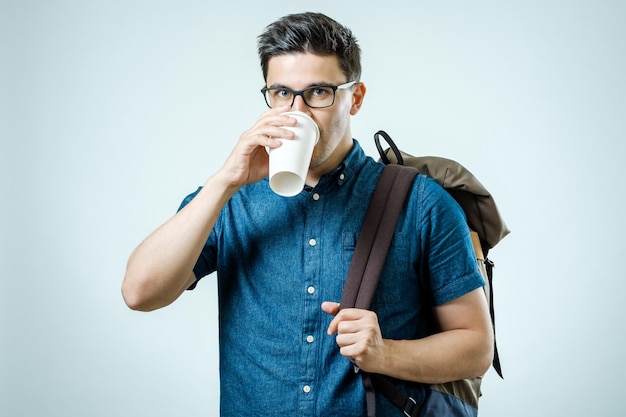 Zeker student Studio portret van knappe jonge man met rugzak geïsoleerd op grijs