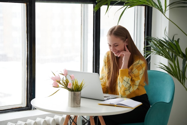 Zekere jonge vrouw in slimme vrijetijdskleding die aan laptop werkt