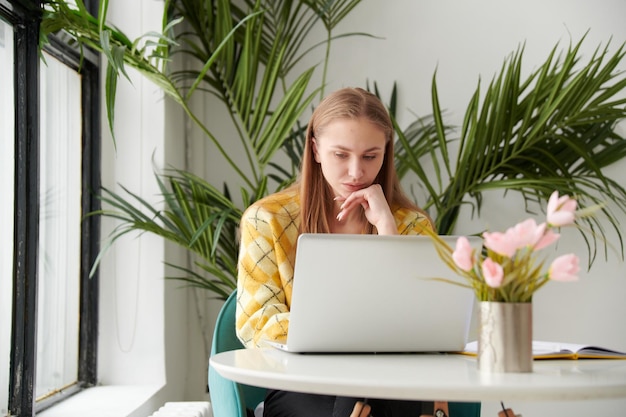 Zekere jonge vrouw in slimme vrijetijdskleding die aan laptop werkt