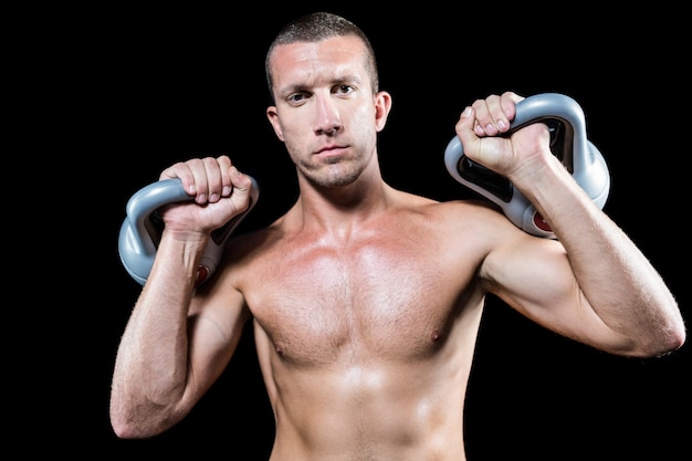 Zekere shirtless atleet holding kettlebell