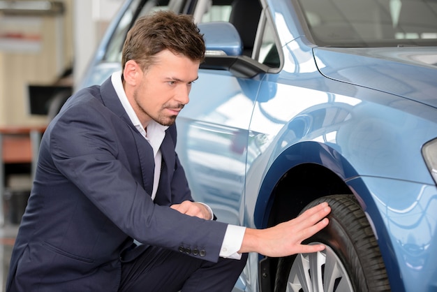 Zekere zakenman die een auto onderzoekt bij het handel drijven.