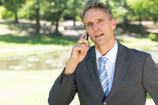 Zekere zakenman die slimme telefoon met behulp van