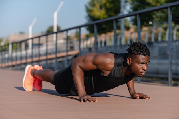 Zekerzinnige Afrikaanse man in sportkleding die pushups doet terwijl hij buiten oefent