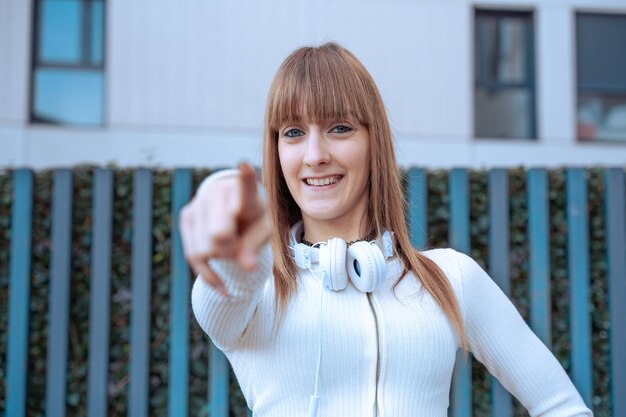 Zekerzinnige en glimlachende jonge vrouw die haar vinger naar voren wijst buiten