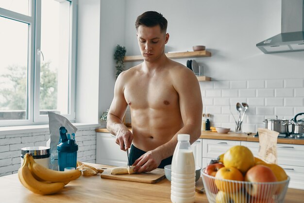 Foto zekerzinnige fitte man die gezond eten bereidt terwijl hij in de keuken staat