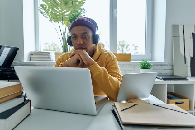 Zekerzinnige man van gemengd ras met koptelefoon op zijn werkplaats