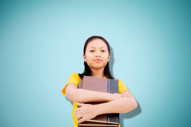 Zekerzinnige vrouwelijke student met boeken in de studio