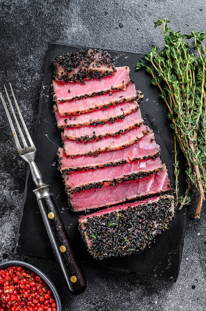 Zeldzame Ahi tonijnsteak plakjes met verse kruiden op een snijplank