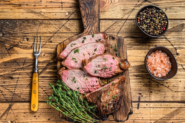 Zeldzame plakjes Rosbief entrecote tri-tip steak bbq op een houten snijplank. houten achtergrond. Bovenaanzicht.