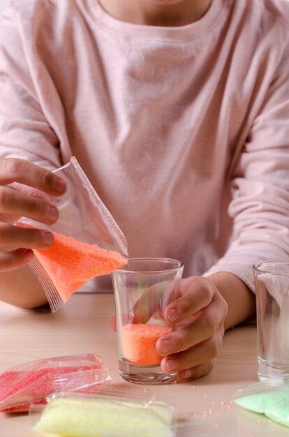 Foto zelf kaarsen maken. klein meisje maken kaars in het glas van sojawas peterselie vlokken.