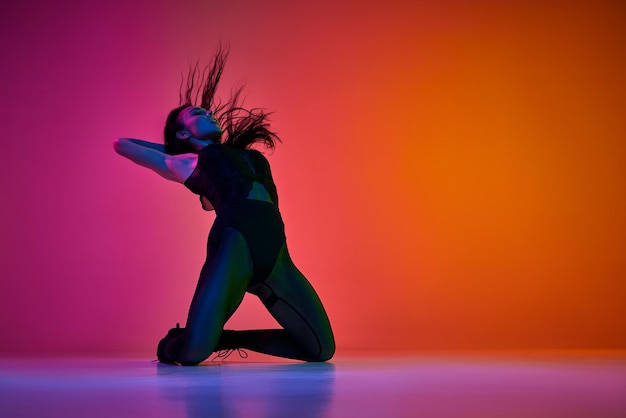 Foto zelfexpressie door bewegingen jonge vrouw die danst op hoge hakken dansstijl over gradiënt roze