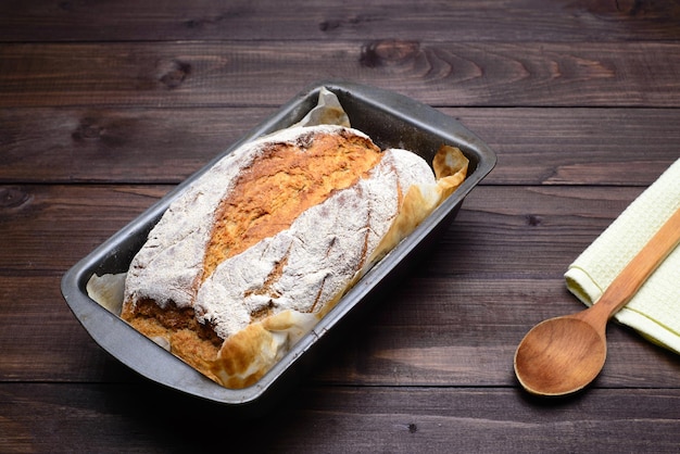 Zelfgebakken brood Deeg in rijsmand op houten tafel met bloem, komijn en tarweoren, kopieer ruimte