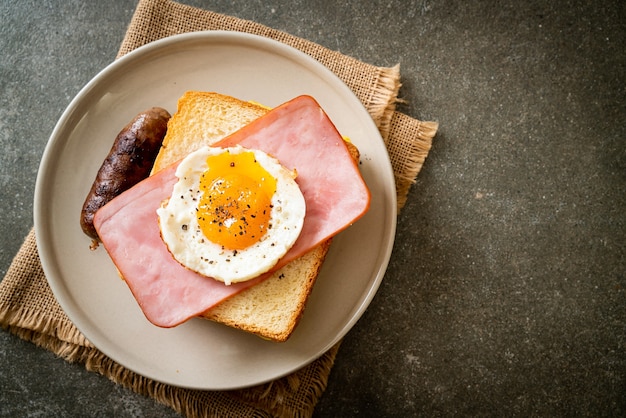 Zelfgebakken brood geroosterde kaas belegd ham en gebakken ei met varkensworst als ontbijt