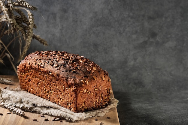 Zelfgebakken brood. Gezond tarwe- en roggebrood met zaden bij plundering, close-up met selectieve focus. Natuurlijk gefermenteerd brood, gezonde voeding. Brood op grijze achtergrond met ruimte voor tekst