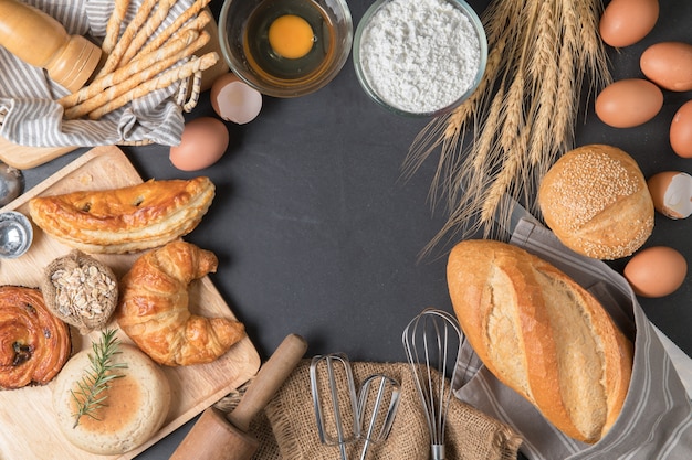 Zelfgebakken brood of bakkerij met vers ei, meel en bakkerijmateriaal op zwarte steen