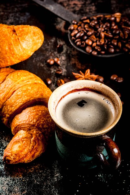 Zelfgemaakt continentaal ontbijt, koffie met kruiden, rietsuiker, croissants. jam op een zwarte roestige metalen tafel,