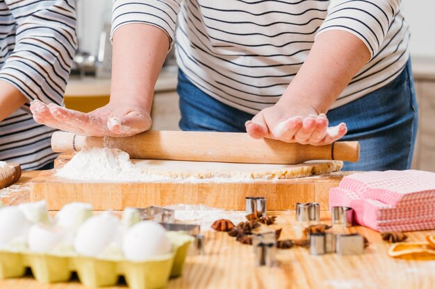 Foto zelfgemaakt gebak close-up van vrouwenhanden die deeg in bloem rollen die peperkoekkoekjes maken